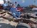 1987 Ford Ranger - A man sits on the frame of a disassembled truck, with other vehicle parts visible in the yard.