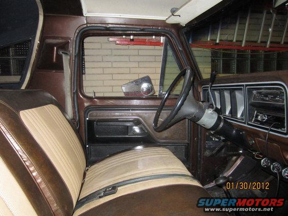 Interior of a brown and tan vehicle, showing the seats, steering wheel, and dashboard