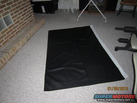 black vinyl sheet on carpet next to a brick fireplace and weight bench