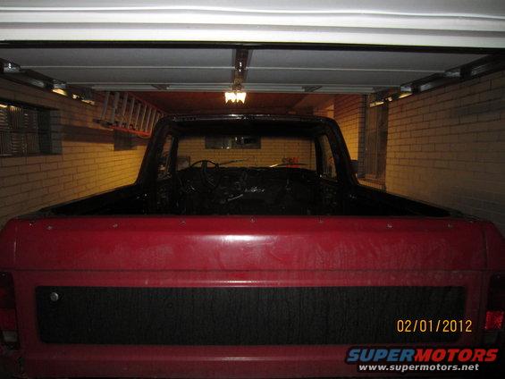 Red pickup truck interior, black dashboard and steering wheel visible, in a garage