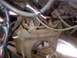 1965 Ford Mustang - Close-up view of rusty suspension components, hoses, and wiring in an engine bay.
