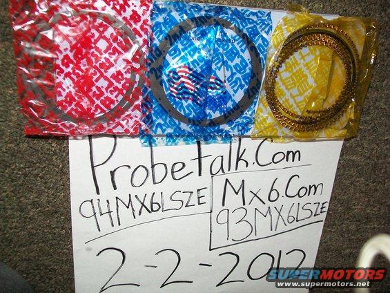 Three sets of piston rings in red, blue, and yellow packaging