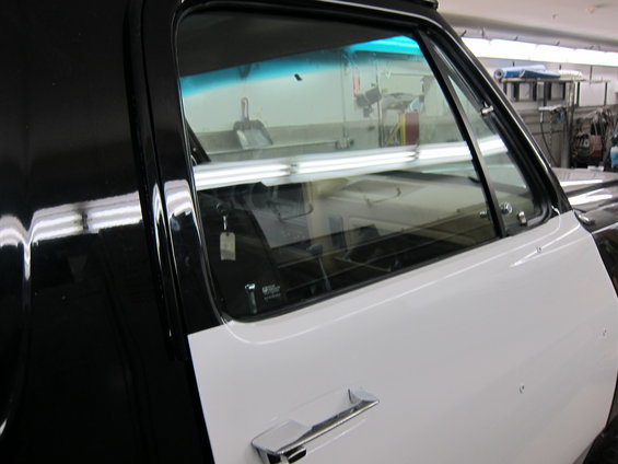 Side view of a black and white truck door and window. Chrome door handle visible