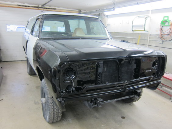 Black and white SUV, front end disassembled, in a garage