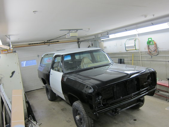 1987 Dodge Ramcharger SUV with black and white primer panels in a garage