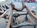 1987 Ford Ranger - A disassembled vehicle frame and axle sit on jack stands, with spare tires piled to the side.