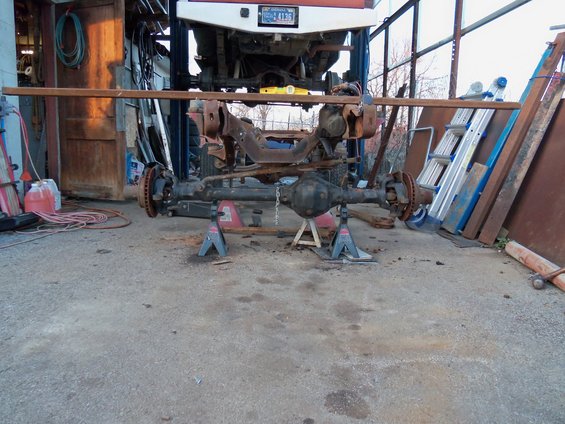 Front axle assembly on jack stands, part of a vehicle lifted above