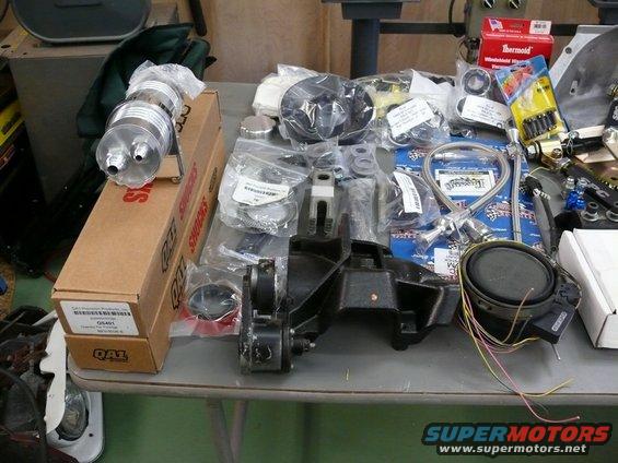 Assorted car parts including a chrome oil filter, engine mount, and speaker