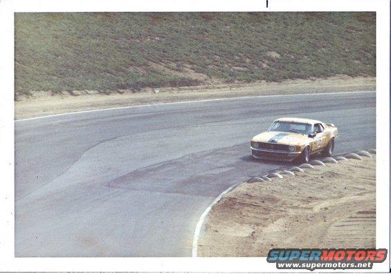 yellow race car with black stripes on a track corner
