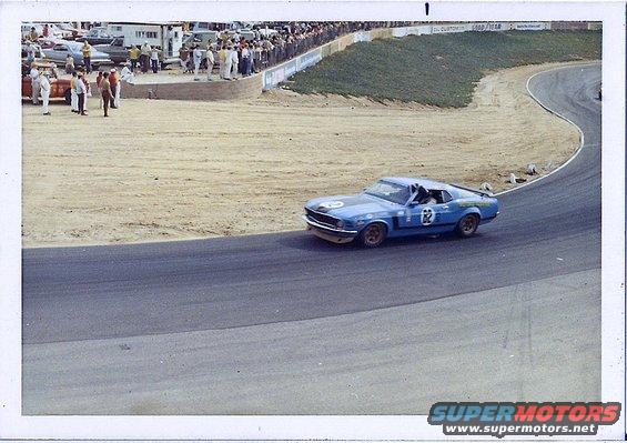 Blue race car with number 62 on door and hood, on a race track