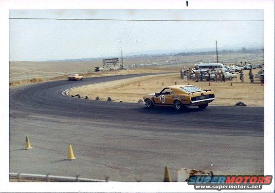 Yellow 1970 race car with number 16 on a track, rear view