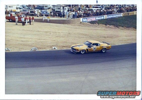 yellow race car with black stripes and number 16 on door, on a track