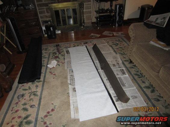 Dark brown interior trim piece laid out on newspaper with white paper