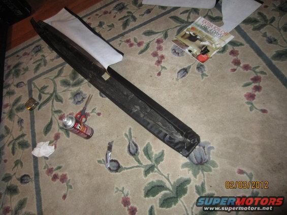 Black interior trim piece on floral carpet with scissors and spray can
