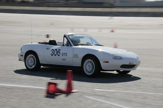 White 1991 Mazda Miata with racing numbers on track