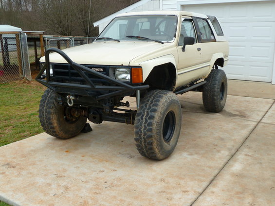 Lifted Toyota 4Runner with custom front bumper and large off-road tires parked on a concrete driveway