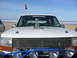 1988 Ford Bronco - This white SUV, likely from 1992, is parked on the beach with a trophy displayed on its hood.