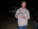 1988 Ford Bronco - A man proudly holds a trophy, with a white SUV visible in the dimly lit background.