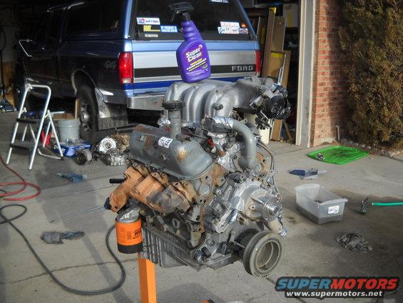 V8 engine on an orange engine stand, with a blue Ford truck in the background