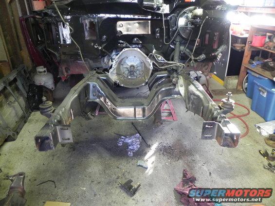 Vehicle frame with engine and transmission removed, showing the chassis and suspension components in a workshop