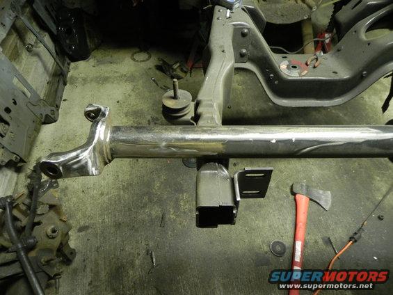 Chrome-plated suspension component with welded brackets and an axe on a workshop floor