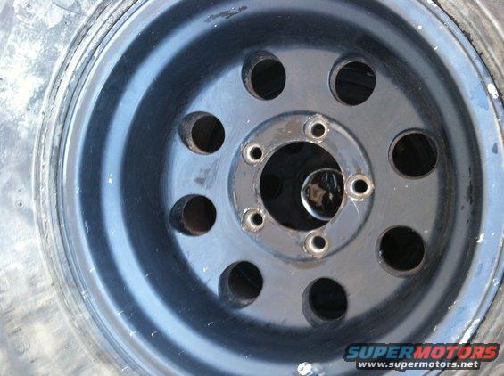 Black steel wheel with five lug nuts and a tire