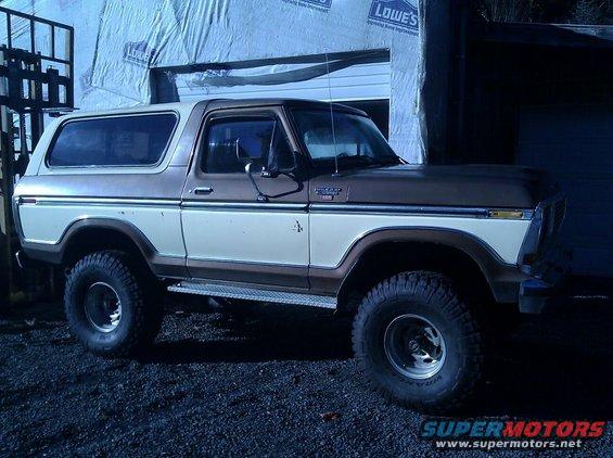 Brown and white Ford Bronco parked in front of a garage under construction