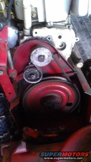 Red engine belt and pulley system with visible oil residue