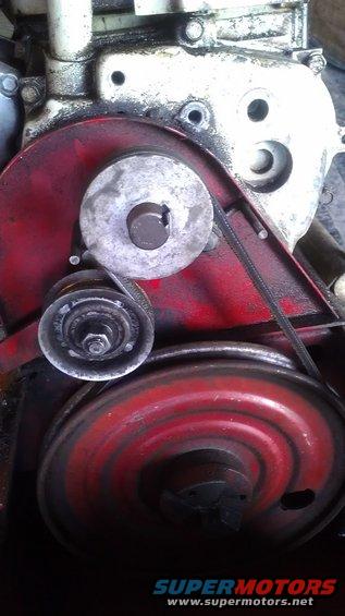 Close-up of engine belt pulleys and belt on a red painted component