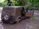 1987 Mazda RX-7 - A muddy Jeep Wrangler is stuck in a ditch, with two people standing nearby in a wooded area.