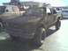 1987 Mazda RX-7 - A heavily mud-caked pickup truck sits parked, with another vehicle partially visible to its left.