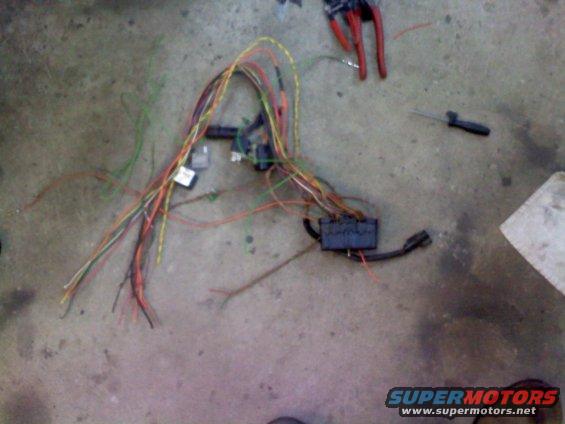 Wiring harness with multiple colored wires and two black boxes on a concrete floor