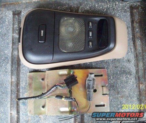 Overhead console with buttons labeled GARAGE, LAMP, MODE, and a light lens, with wiring harness attached to a metal bracket