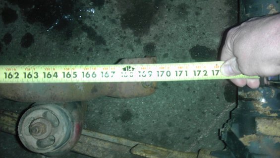 Measuring tape on rusty suspension component. Tape reads from 162 to 172