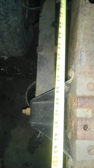 Leaf spring and black suspension bracket with yellow tape measure showing inches