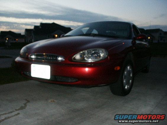 Red sedan parked on concrete driveway at dusk