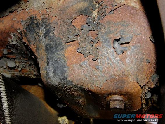 Heavily rusted metal part with peeling paint and a hex bolt