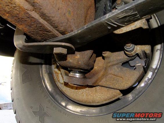 Close-up of rusty rear suspension leaf spring and brake drum assembly