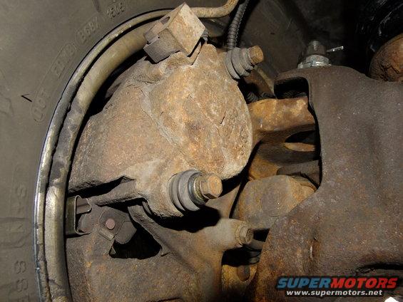 Close-up of a rusty vehicle brake caliper and rotor assembly