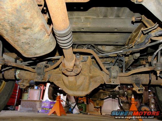 1995 Ford Bronco rear axle and suspension with heavy rust and orange jack stands
