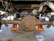 1995 Ford Bronco - The rear axle assembly of a vehicle is shown, supported by orange jack stands, with various suspension and exhaust components visible.