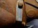 1995 Ford Bronco - A heavily corroded metal tag is attached to a rusty chassis part, showing stamped alphanumeric characters.