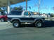 1986 Ford Bronco - This two-tone Ford Bronco, likely from the early 1980s, is parked at a gas station with a red SUV nearby.