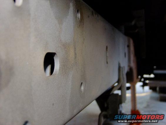 Close-up of a vehicle's frame rail with several holes
