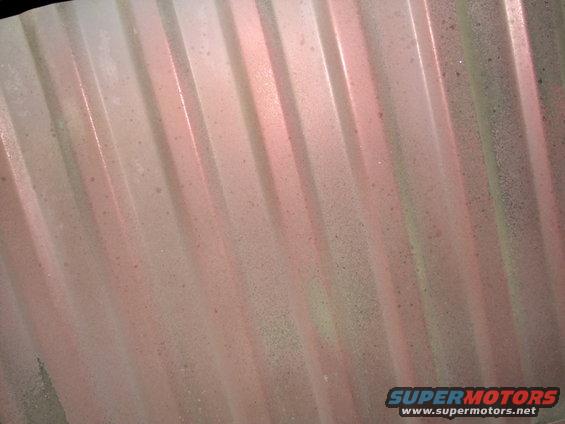 Corrugated metal surface with pink and green overspray