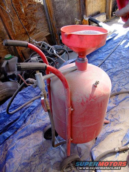 Red sandblaster with a funnel on top, sitting on a blue tarp