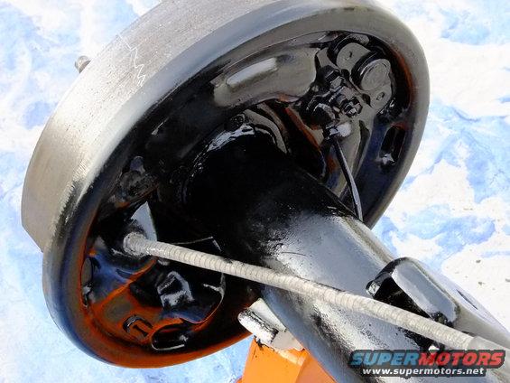 Rear axle and brake drum assembly with black painted components and a metal cable