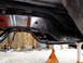 1995 Ford Bronco - The underside of a vehicle's chassis has been freshly painted and is supported by jack stands in a workshop.