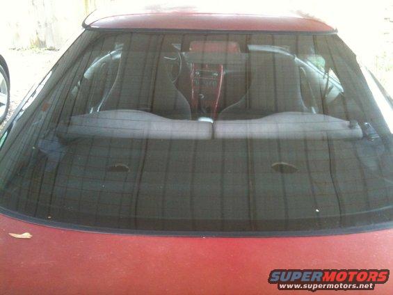 Red car interior with bucket seats visible through rear window