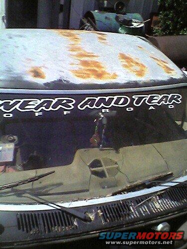 Rusted hood and windshield of a vehicle with "WEAR AND TEAR OFFROAD" sticker